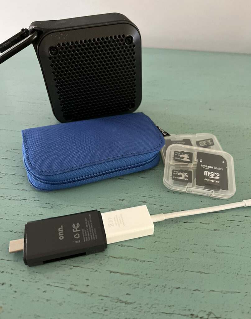 A photo of a speaker, SD Cards, SD Card Holder and SD Card Reader on a blue desk